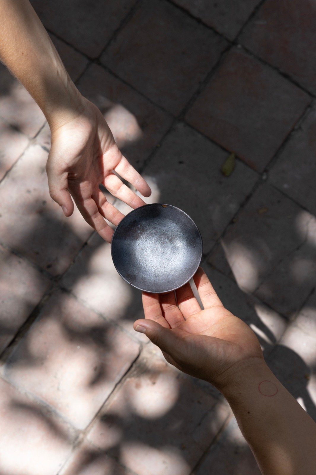 Two hands passing a ceramic bowl
